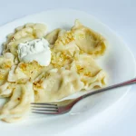 Pierogi z cebulką i śmietaną na talerzu