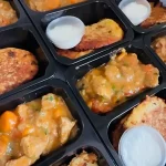 Zestawy obiadowe z plackami ziemniaczanymi i gulaszem w pojemnikach cateringowych