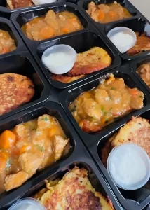 Zestawy obiadowe z plackami ziemniaczanymi i gulaszem w pojemnikach cateringowych