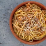 Spaghetti bolognese na czerwonym talerzu